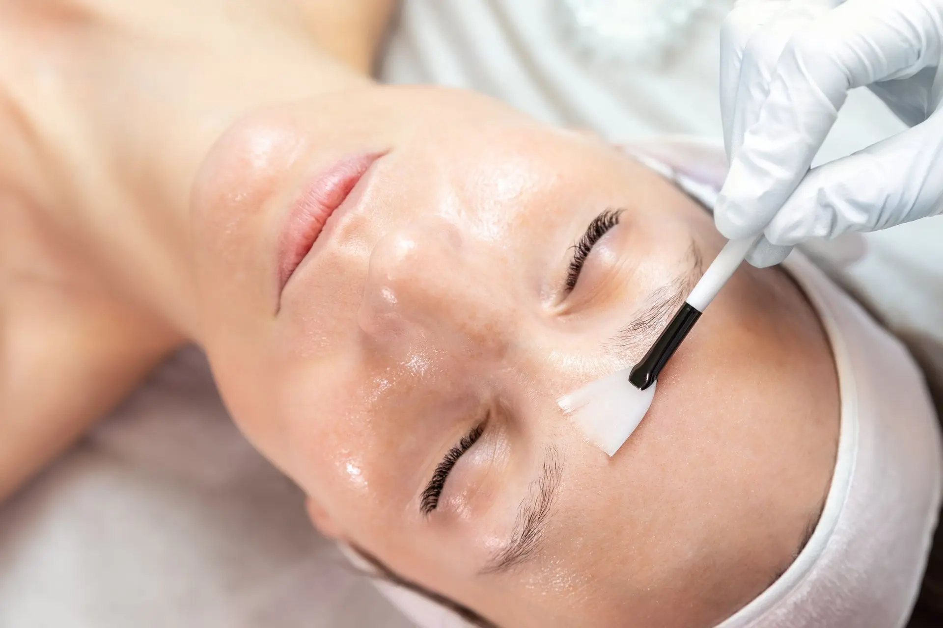 Woman receiving a facial treatment with a transparent gel mask